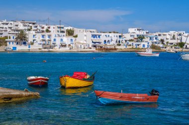 Ano Koufonisi, GR - 9 Eylül 2025: Köyün geleneksel beyaz evleri arka planda görünür durumda olan çeşitli renkli tekneler denize demirlemiştir