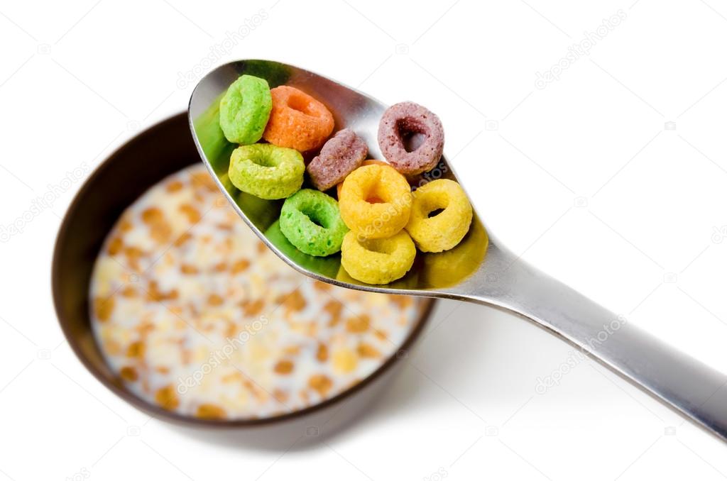 Close up of a spoon above a bowl with cereals and milk, isolated