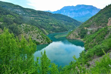 Koman Gölü 'nün turkuaz suları kuzey Arnavutluk' un yüksek kayalık dağlarıyla çevrilidir.