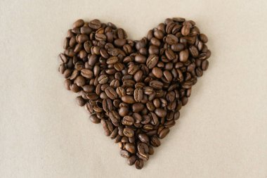 Bej arkaplanda kalp şeklinde kavrulmuş kahve çekirdekleri.