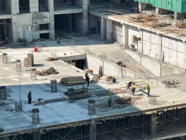 İnşaat işçisi grubu bir binanın beton zemininde çalışıyor. mimari ve mühendislik ilerleme kavramı.