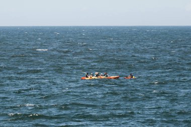 Güneşli bir günde, yaz macerasında açık okyanusta kayak yapan bir grup insan. Açık deniz sporları aktivitesi ve takım çalışması