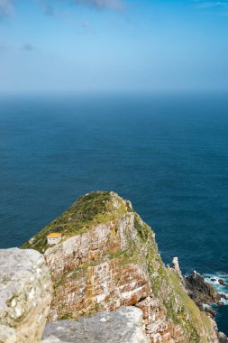 Ümit Burnu uçurumu, Güney Afrika 'daki mavi Atlantik Okyanusu kıyısında küçük beyaz bir ev. Seyahat ve turizm için kıyı manzarası.