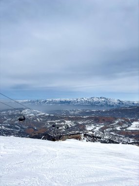 Özbekistan 'daki Amirsoy kayak merkezinde karlı dağlara bakan teleferikli kayak pisti. Seyahat broşürleri için kış dağı manzarası.