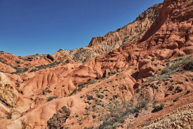 Kırmızı kil kanyon ve açık mavi gökyüzü manzaralı kayalık dağ. Çöl ülkesi. Seyahat ve macera için doğal zemin..