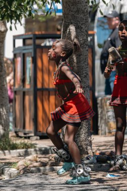 Siyah Afrikalı kız çocuk geleneksel kültür, kültür ve gelenekleri temsil eden geleneksel bir yüz boyası ve kültürel kıyafetle dans ediyor. Cape Town, Güney Afrika - 22 OCT 2023