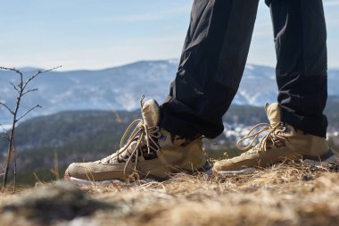 Yürüyüşçü dağ yolunda yürüyor, engebeli yürüyüş botları ve açık hava pantolonları giyiyor, macera ve keşif yolculuğunun tadını çıkarıyor..