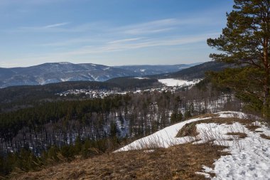 Kış vadisindeki kırsal köy ormanlık tepelerde kar gösteriyor. Seyahat ve tatil için doğal manzara.