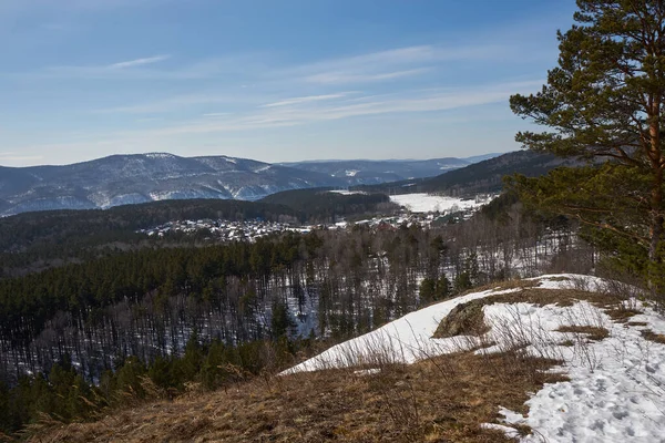 Kış vadisindeki kırsal köy ormanlık tepelerde kar gösteriyor. Seyahat ve tatil için doğal manzara.