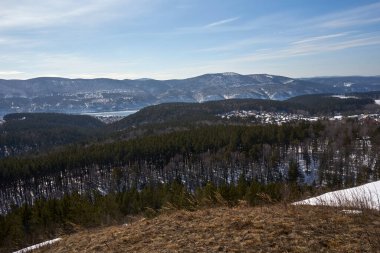 Tepe yamaçlarında ve karlı, yemyeşil ormanları olan güzel kış manzarası. Görkemli doğa manzarası.