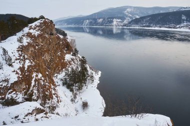 Karla kaplı dağlarla Yenisei nehri manzarası. Seyahat reklamları ve sezon konsepti için kış manzarası. Soğuk hava nehri.