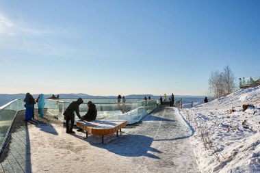 Karlı bir parktaki modern bakış açısına sahip insanlar. Doğa yolculuğu ve açık hava eğlencesi için manzaralı kış manzarası. Nikolaevskaya Sopka, Gremyachaya Griva. Krasnoyarsk, Rusya - 30 Ocak 2022.