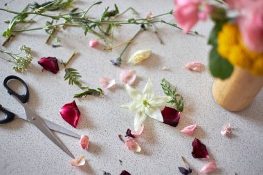 Taze çiçek yaprakları, yeşil yapraklar ve ışık masasına saçılmış makas. Hobi ya da ev dekorasyonu için çiçek aranjmanı ve el işi projesi konsepti.