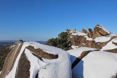 Kar açık mavi gökyüzü altında kaya oluşumlarını kapladı. Doğal kaya parkının kış manzarası seyahat ve doğa keşfi için. Krasnoyarsk Stolby Parkı.