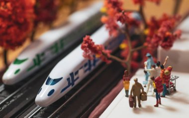Sonbaharda ya da sonbahar mevsiminde yüksek hızlı tren platformunda bekleyen yalnız bir kadının minyatür oyuncak figürleri. Sıcak hava filtresi uygulandı. - Shinkansen model tren..