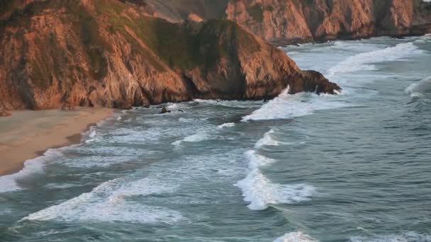 Strand, klippor och vågor vid solnedgången — Stockvideo
