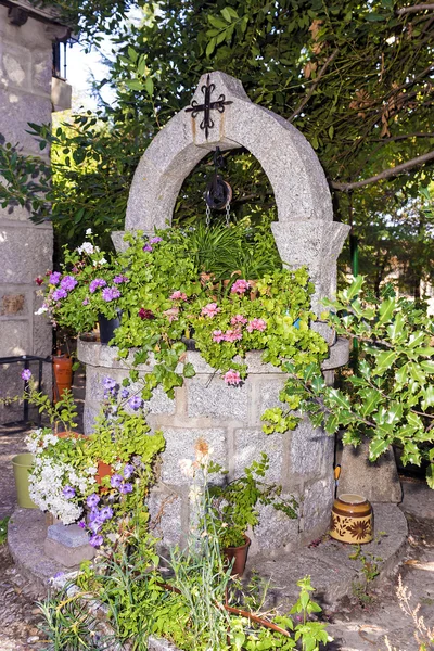 Каменный колодец для воды, украшенный цветами — стоковое фото