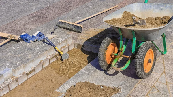 Strumento per la posa di lastre di pavimentazione su uno sfondo di mattoni di granito e miscela sabbia-cemento — Foto Stock