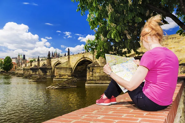 Menina olha para o mapa no fundo de Praga Charles Bridge — Fotografia de Stock