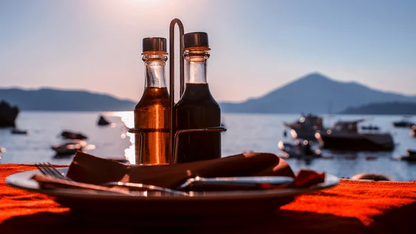 Botella con aceite de oliva sobre un fondo de puesta del sol del mar —  Fotos de Stock