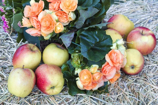 Flowers and apple on hay — Stock Photo, Image