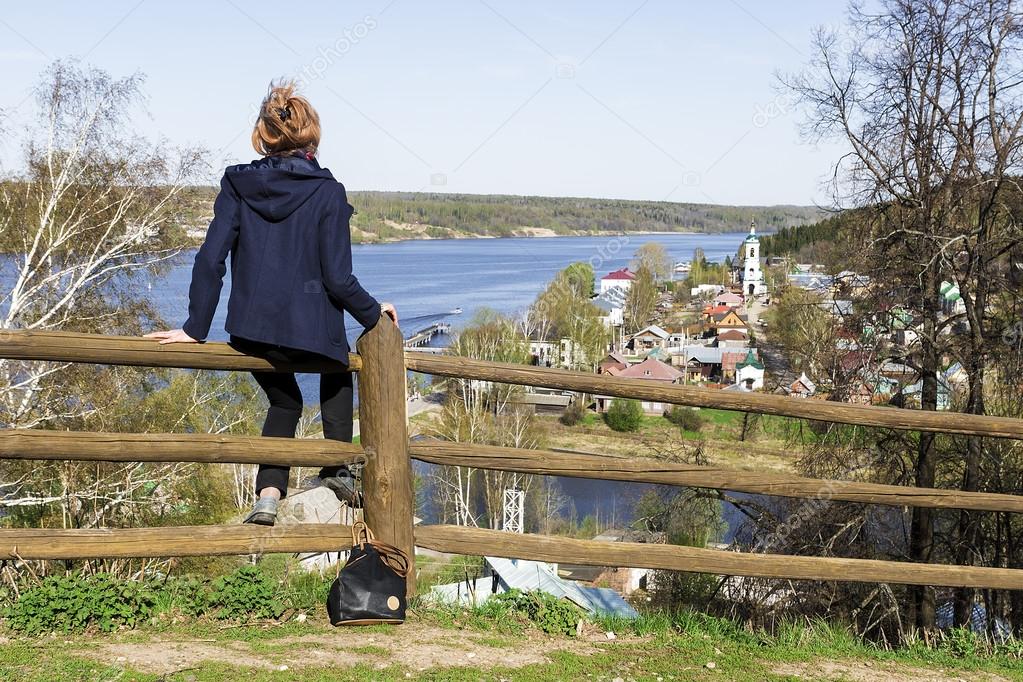 girl sitting on a wooden fence and watching the beautiful town P