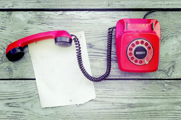 Vintage rode telefoon en een stukje papier om te schrijven — Stockfoto