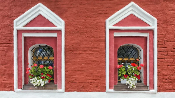 Цегляна будівля, прикрашена квітами герані та петунії — стокове фото