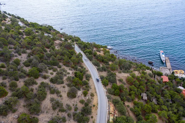 Fragment of a road that runs along the mountainside near the sea. Shooting from a drone.