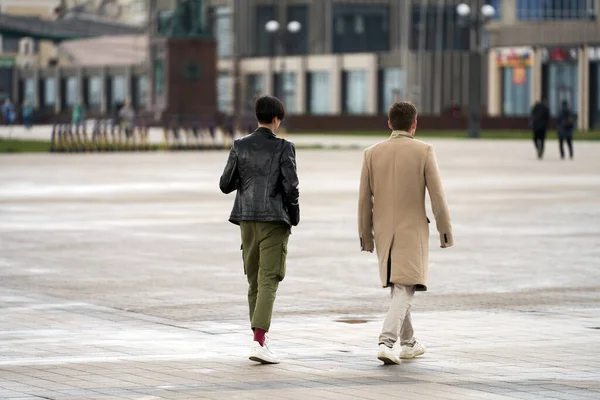 Urban landscape. Young people are walking along the street: a man in a classic style of clothing and a woman in garcon style clothing. Copy space. Selective focus.