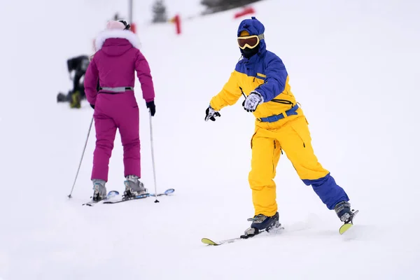 A woman learns the basics of skiing. She goes down the mountain on carving skis. Selective focus.