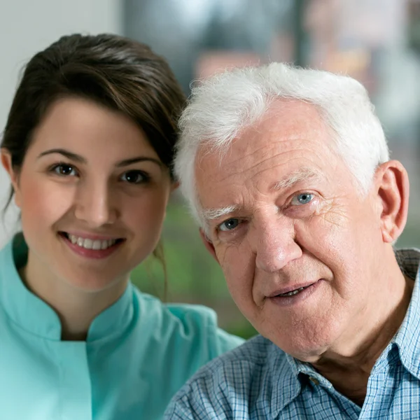 Lachende senior man en jonge verpleegster — Stockfoto