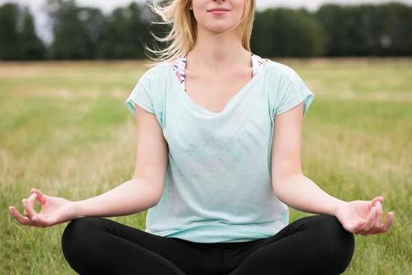 Meditera utanför med benen korsade — Stockfoto