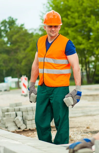 Builder in uniform holding cobbles — Stock Photo, Image