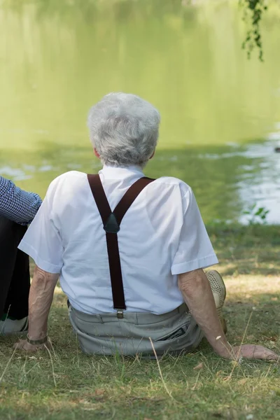 Gepensioneerde zittend op het gras — Stockfoto