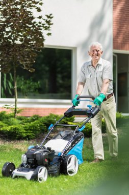 Modern bir çim biçme makinesi kullanarak bahçıvan