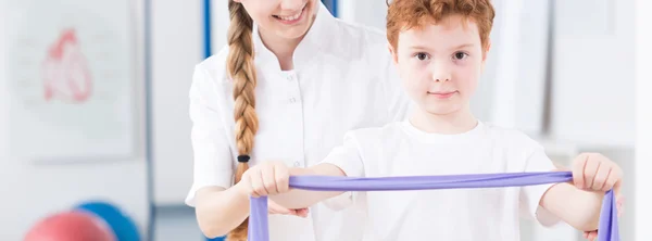 Liten pojke gör en övning med pediatrisk sjukgymnast — Stockfoto