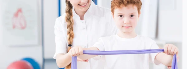 Niño haciendo un ejercicio con fisioterapeuta pediátrico — Foto de Stock