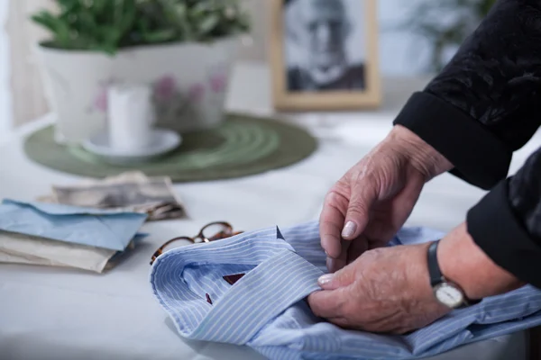 Old woman's hands on men's shirt — Stock Photo, Image