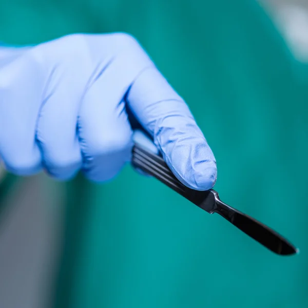 Main du médecin tenant le scalpel — Photo