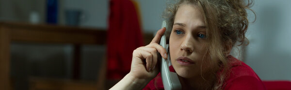 Плачущая девушка разговаривает по телефону
