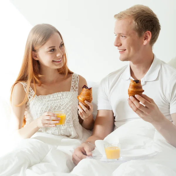 Pareja comiendo croissants en la cama —  Fotos de Stock