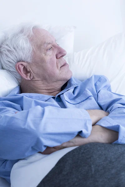 Paciente idoso deitado no leito hospitalar — Fotografia de Stock