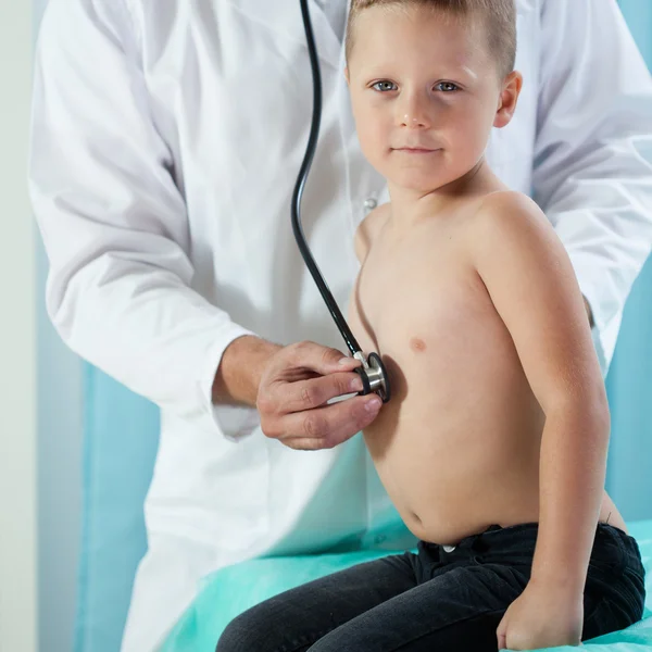 Pequeño paciente sentado en el sofá de examen — Foto de Stock