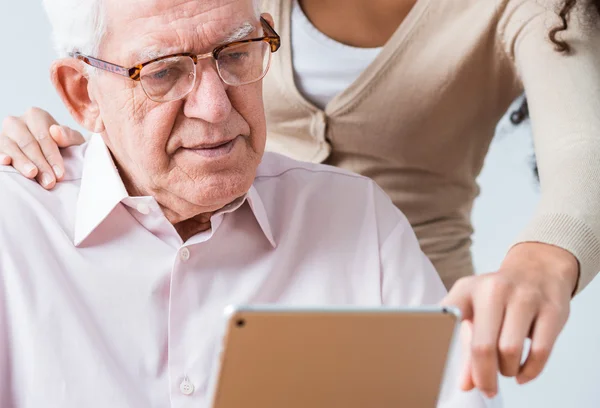 Женщина помогает пожилому мужчине читать анкету — стоковое фото