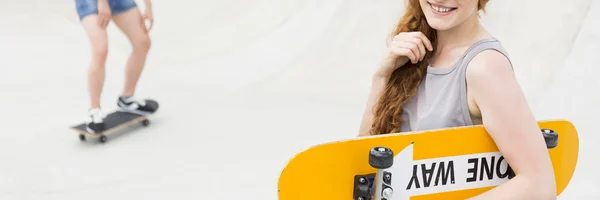 Крутая девушка-фигуристка и её скейтборд — стоковое фото
