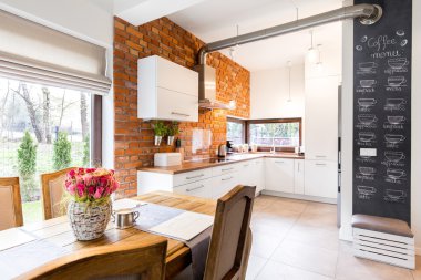Spacious kitchen with white furniture and brick wall clipart
