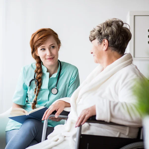 Mujer en silla de ruedas con médico — Foto de Stock