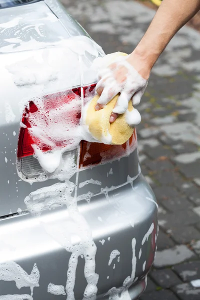 Человек, использующий пену для чистки автомобиля — стоковое фото