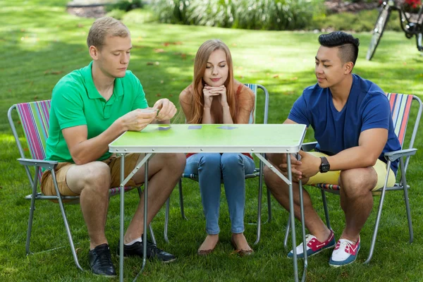 Vrienden speelkaarten in een tuin — Stockfoto